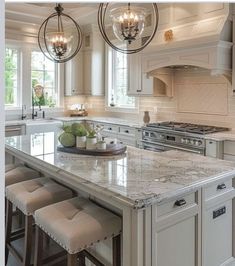 a large kitchen island with stools in front of it and two chandeliers hanging from the ceiling