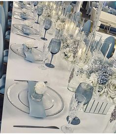 the table is set with blue and white flowers, silverware, and candlesticks