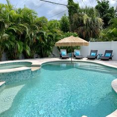 an outdoor pool with lounge chairs, umbrella and palm trees in the backround