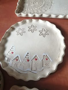 two pie pans sitting on top of a table next to plates with houses and snowflakes