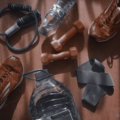 an assortment of athletic equipment including shoes, water bottle and headphones on a bed