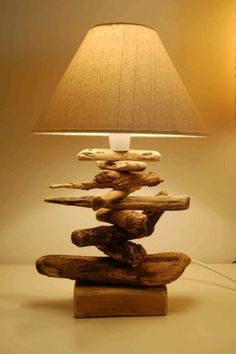 a lamp that is sitting on top of a wooden base with rocks stacked up in the shape of a boat