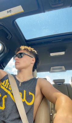 a young man sitting in the back seat of a car wearing sunglasses and a bandana