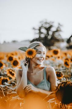 a woman smiles as she talks on her cell phone in a field of sunflowers