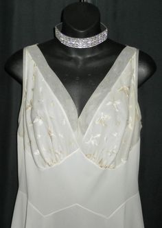 "Made by Vanity Fair, color is an off white, antique white, light beige, whichever you would like to call it, so pretty. This halter style gown is ultra flattering with satin stitched embroidery on the bust and chiffon trim on the bodice and hemline. I do see some light colored stains on the lower half of the gown, you may be able to see them in the photo of the hemline. I did launder but they didn't seem to come out. Relatively light so they aren't as obvious. Bust 38\" Waist 32\" Hips up to 46 Elegant Cream Wedding Nightgown, Elegant White Nightgown With Bias Cut, Feminine White Nightgown For Evening, Elegant White Bias Cut Nightgown, Feminine White Evening Nightgown, Elegant White Party Nightgown, Fitted Cream Nightgown For Wedding, White Sleeveless Nightgown For Party, White Sleeveless Party Nightgown