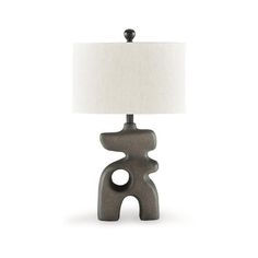 a table lamp with a white shade on top of it and a black object in the middle