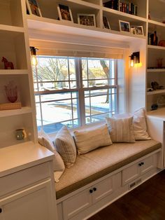 a window seat in the corner of a room with bookshelves on either side