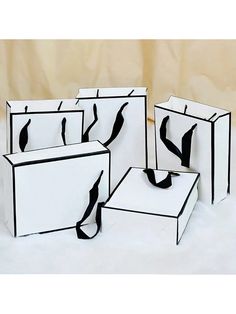 four white boxes with black ribbons on them