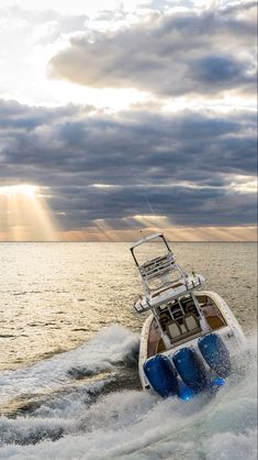 a boat is traveling through the water on a cloudy day with sunbeams in the background