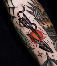 an arm with some tattoos on it and a knife in the middle, surrounded by other items