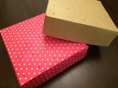 two boxes are stacked on top of each other, one with white polka dots and the other red