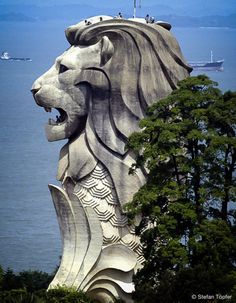 the lion statue is in front of the water and boats are out on the ocean