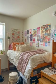 a bed room with a neatly made bed and lots of pictures on the wall above it