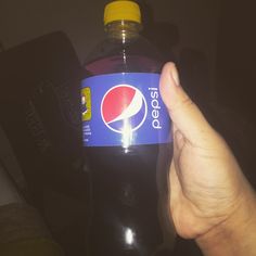 a hand holding up a bottle of pepsi soda