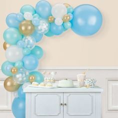 blue and gold balloons are hanging from the ceiling above a buffet table with desserts on it