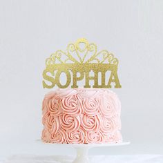 a cake with pink frosting and gold glitter topper that says'emma is one '