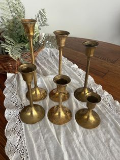 four brass candlesticks sitting on top of a white doily