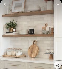 a kitchen with white cabinets and wooden shelves