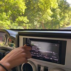 a person driving a car while holding the steering wheel and looking at an electronic screen