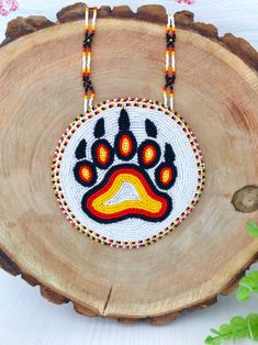 a beaded necklace with an animal's paw on it sitting on top of a piece of wood