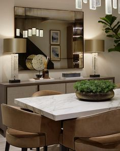 a dining room table with four chairs and a vase on top of it in front of a mirror