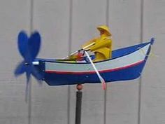 a toy boat with a man in it and a blue heart shaped fan behind it