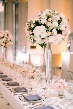 a long table with white and pink flowers in vases on top of the tables