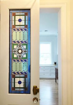 an open door with a stained glass window in the center and wooden flooring on the other side