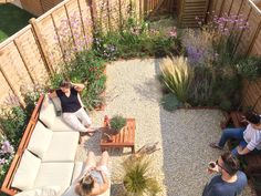 three people sitting on couches in a small garden area with graveled ground and wooden planters