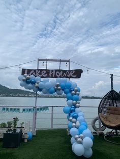 balloon arch with lake house sign and blue balloons in front of the water at an outdoor event