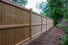 a wooden fence is next to a dirt path