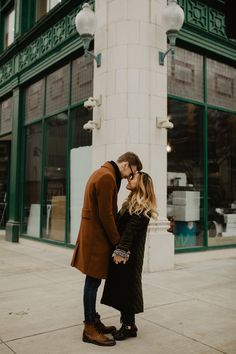 a man and woman standing next to each other on the sidewalk in front of a building