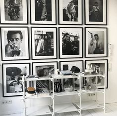 black and white photographs hang on the wall above a shelf with various items in front of it