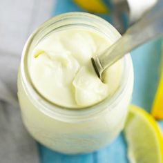 a spoon in a jar filled with yogurt next to sliced lemons and lime wedges