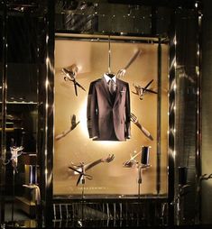 a suit and tie on display in a glass case with lights hanging from the ceiling