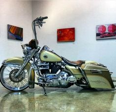 a gold and black motorcycle is parked in a room with pictures on the wall behind it