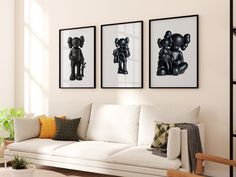 three black and white pictures hang on the wall above a couch in a living room