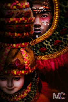 a woman with painted face and headdress standing in front of a mirror