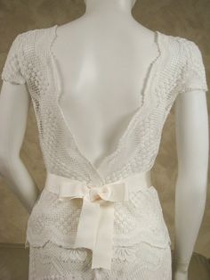 a mannequin wearing a white dress with a bow at the waist