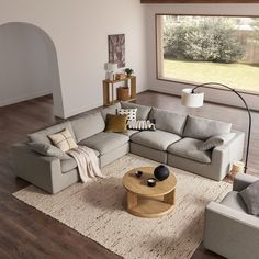 a living room filled with furniture next to a large window and wooden floored floors