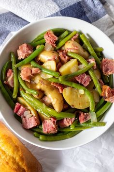 a white bowl filled with green beans and ham on top of a blue and white checkered table cloth