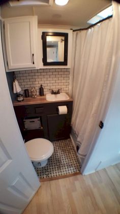 a small bathroom with a toilet, sink and shower in it's stall door