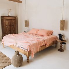 a bed sitting in a bedroom next to a wooden dresser and table with two vases on it