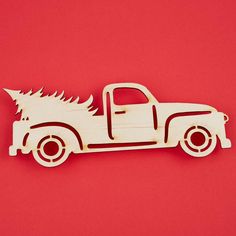 a wooden toy truck with a christmas tree on the back in front of a red background