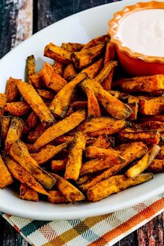 air fryer spicy sweet potato fries on a plate with dipping sauce in the background