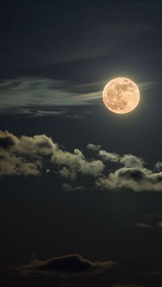 the full moon shines brightly in the night sky above some clouds and dark blue skies