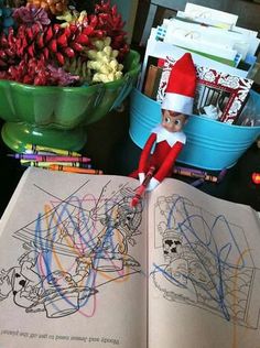 an elf is sitting on the table and reading a book with colored crayons