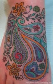 a colorful tattoo on the foot of a person's left hand with flowers and paisley designs