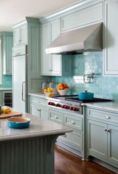 a kitchen with blue cabinets and white counter tops, an island in the middle has fruit on it