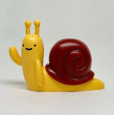 a yellow toy snail with a red shell on it's back and its eyes closed